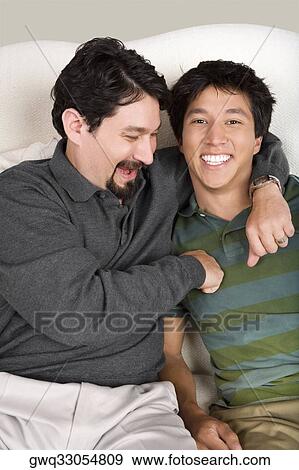 Stock Photo - Mid adult man with his arm around his son. Fotosearch