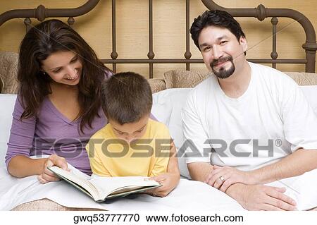 Stock Image - Mid adult woman teaching her son with a mid adult man sitting beside them. Fotosearch