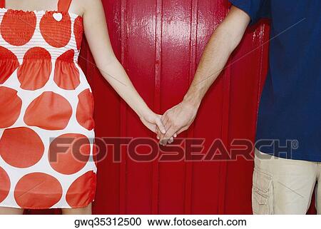 Mid section view of a couple holding hands View Large Photo Image Stock Image - Mid section view of a couple holding hands. Fotosearch