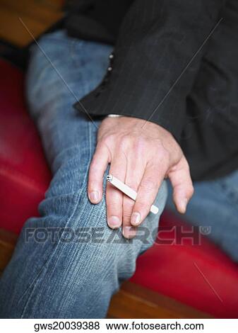 Mid section view of a man holding a cigarette View Large Photo Image Stock Photo - Mid section view of a man holding a cigarette. Fotosearch