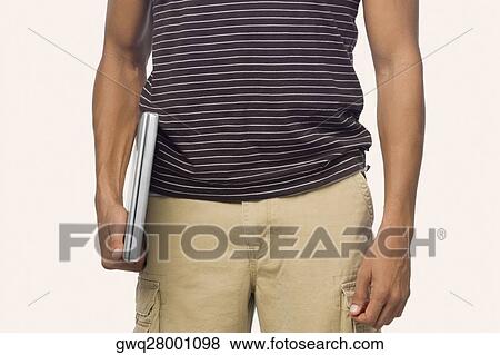 Mid section view of a mid adult man holding a laptop View Large Photo Image Stock Photo - Mid section view of a mid adult man holding a laptop. Fotosearch
