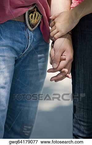 Mid section view of a young couple holding hands of each other View Large Photo Image Stock Photo - Mid section view of a young couple holding hands of each other. Fotosearch