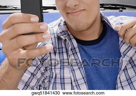 Mid section view of a young man holding a mobile phone View Large Photo Image Stock Image - Mid section view of a young man holding a mobile phone. Fotosearch
