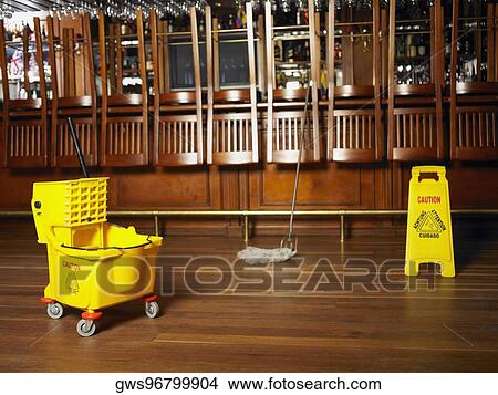 Mop and a warning sign in front of a bar counter View Large Photo Image Picture - Mop and a warning sign in front of a bar counter. Fotosearch