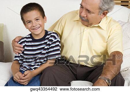 Portrait of a boy sitting with his grandfather on a couch and smiling View Large Photo Image Stock Image - Portrait of a boy sitting with his grandfather on a couch and smiling. Fotosearch
