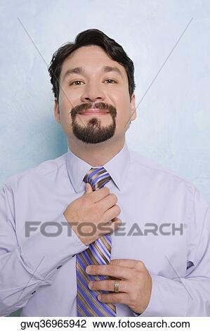 Stock Image - Portrait of a businessman adjusting his tie. Fotosearch