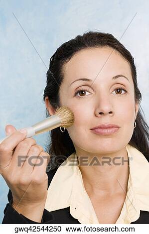 Portrait of a businesswoman applying make-up on her face with a make-up brush View Large Photo Image Stock Image - Portrait of a businesswoman applying make-up on her face with a make-up brush. Fotosearch