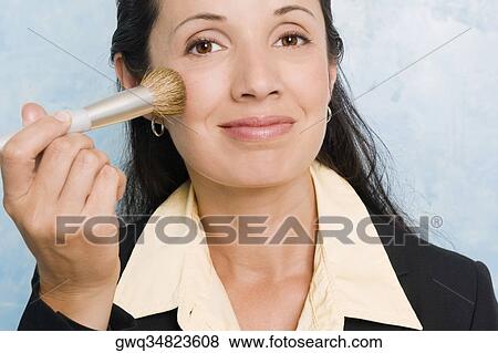 Portrait of a businesswoman applying make-up on her face with a make-up brush View Large Photo Image Stock Photo - Portrait of a businesswoman applying make-up on her face with a make-up brush. Fotosearch