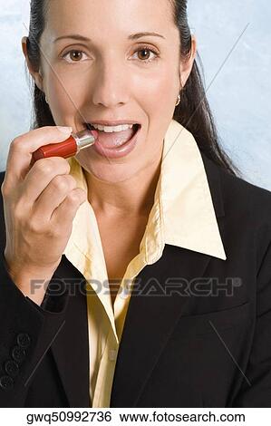 Portrait of a businesswoman applying lipstick on her lips View Large Photo Image Stock Photograph - Portrait of a businesswoman applying lipstick on her lips. Fotosearch