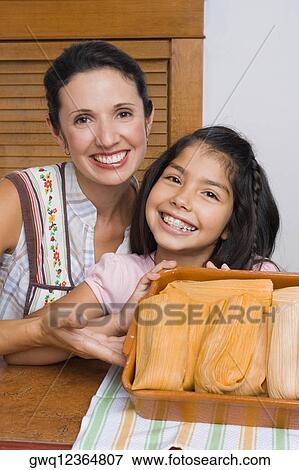 Portrait of a girl and her mother smiling with a tray of breads in the kitchen View Large Photo Image Stock Photo - Portrait of a girl and her mother smiling with a tray of breads in the kitchen. Fotosearch