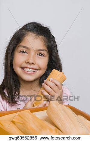 Stock Photograph - Portrait of a girl holding a bread and smiling in the kitchen. Fotosearch