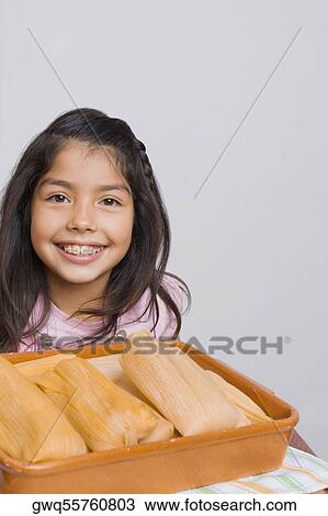 Stock Image - Portrait of a girl smiling with a tray of breads in the kitchen. Fotosearch