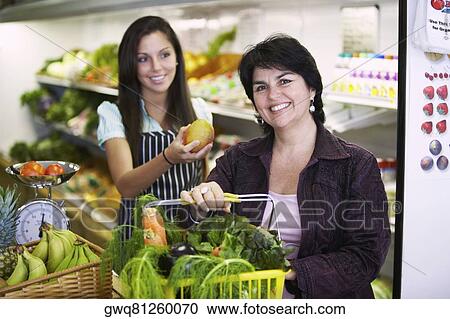 Portrait of a mature woman holding a shopping basket and a female sales clerk giving her a mango View Large Photo Image Stock Image - Portrait of a mature woman holding a shopping basket and a female sales clerk giving her a mango. Fotosearch