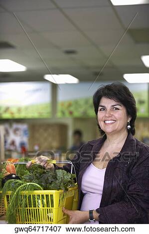 Portrait of a mature woman holding a shopping basket and smiling View Large Photo Image Stock Photo - Portrait of a mature woman holding a shopping basket and smiling. Fotosearch