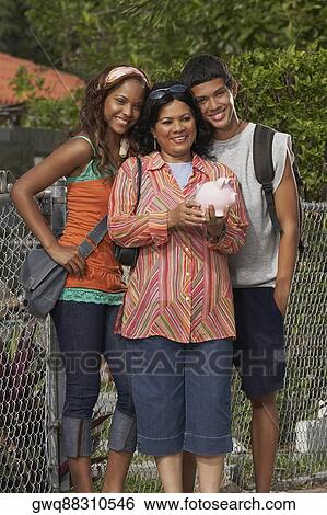 Portrait of a mature woman holding a piggy bank while standing with her daughter and son View Large Photo Image Stock Photograph - Portrait of a mature woman holding a piggy bank while standing with her daughter and son. Fotosearch