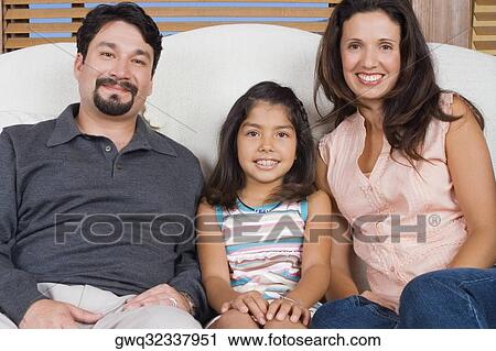 Portrait of a mid adult couple sitting on a couch with their daughter and smiling View Large Photo Image Stock Image - Portrait of a mid adult couple sitting on a couch with their daughter and smiling. Fotosearch