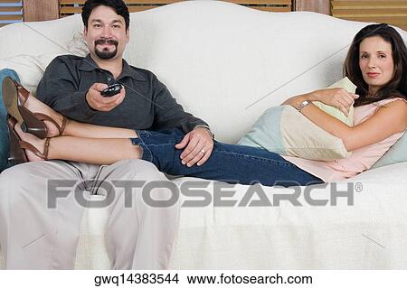 Portrait of a mid adult couple watching television View Large Photo Image Picture - Portrait of a mid adult couple watching television. Fotosearch