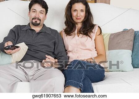 Portrait of a mid adult couple watching television View Large Photo Image Stock Image - Portrait of a mid adult couple watching television. Fotosearch