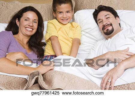 Portrait of a mid adult couple with their son on the bed View Large Photo Image Stock Photography - Portrait of a mid adult couple with their son on the bed. Fotosearch