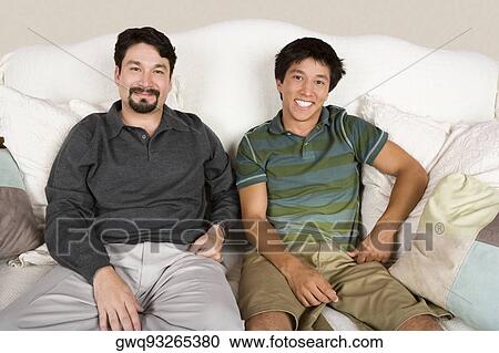 Portrait of a mid adult man and his son sitting on a couch and smiling View Large Photo Image Stock Image - Portrait of a mid adult man and his son sitting on a couch and smiling. Fotosearch