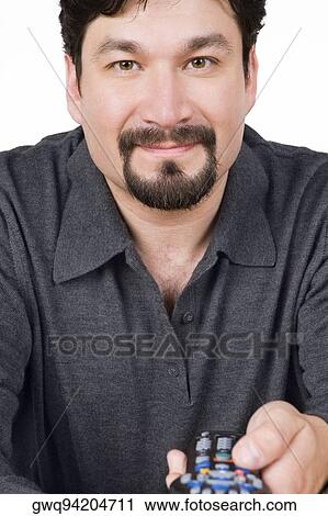 Stock Image - Portrait of a mid adult man holding a remote control and smirking. Fotosearch