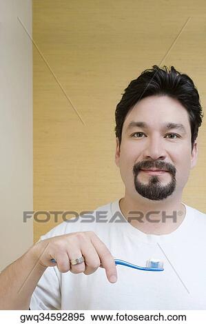 Stock Photography - Portrait of a mid adult man holding a toothbrush. Fotosearch