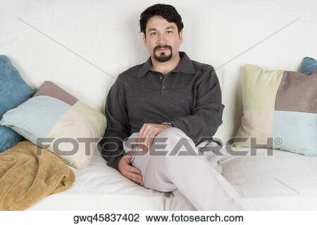 Portrait of a mid adult man sitting on a couch View Large Photo Image Stock Image - Portrait of a mid adult man sitting on a couch. Fotosearch