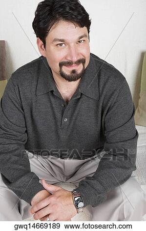 Portrait of a mid adult man sitting on a couch and smirking View Large Photo Image Stock Photo - Portrait of a mid adult man sitting on a couch and smirking. Fotosearch