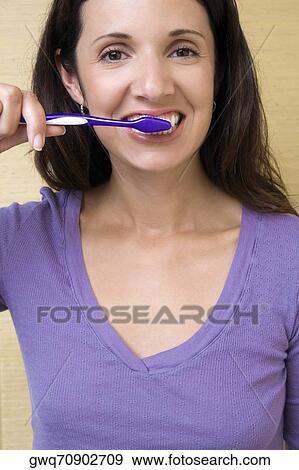 Stock Photo - Portrait of a mid adult woman brushing her teeth. Fotosearch