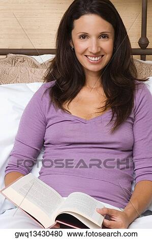 Portrait of a mid adult woman holding a book and smiling View Large Photo Image Stock Image - Portrait of a mid adult woman holding a book and smiling. Fotosearch