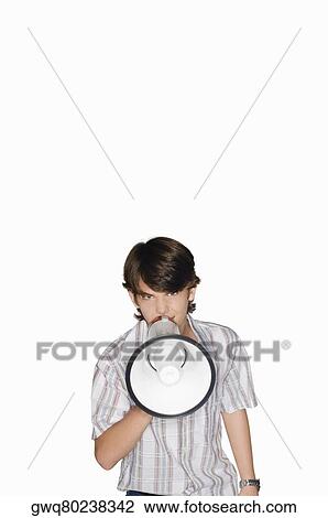 Stock Image - Portrait of a teenage boy blowing a bullhorn. Fotosearch