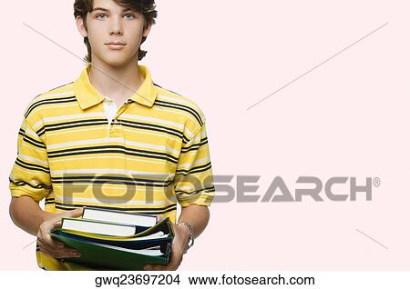 Portrait of a teenage boy holding books and ring binders View Large Photo Image Picture - Portrait of a teenage boy holding books and ring binders. Fotosearch