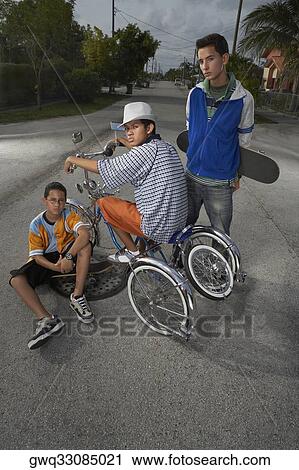 Portrait of a teenage boy on a low rider bicycle with his two friends beside him View Large Photo Image Stock Image - Portrait of a teenage boy on a low rider bicycle with his two friends beside him. Fotosearch