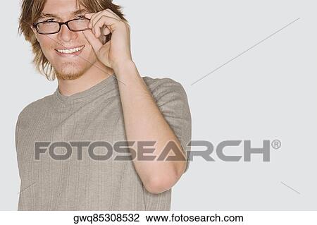 Portrait of a young man adjusting his eyeglasses and smiling View Large Photo Image Stock Image - Portrait of a young man adjusting his eyeglasses and smiling. Fotosearch