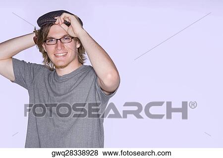 Portrait of a young man adjusting his flat cap and smiling View Large Photo Image Stock Photo - Portrait of a young man adjusting his flat cap and smiling. Fotosearch