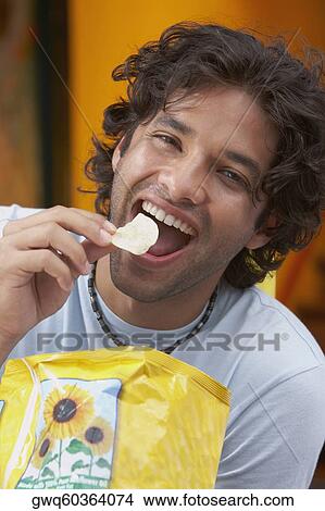 Portrait of a young man eating potato chips View Large Photo Image Picture - Portrait of a young man eating potato chips. Fotosearch