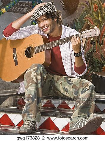 Portrait of a young man holding a guitar and smiling View Large Photo Image Stock Image - Portrait of a young man holding a guitar and smiling. Fotosearch