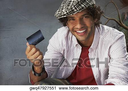 Portrait of a young man holding a credit card and smiling View Large Photo Image Stock Image - Portrait of a young man holding a credit card and smiling. Fotosearch