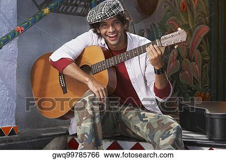 Stock Photograph - Portrait of a young man holding a guitar and smiling. Fotosearch