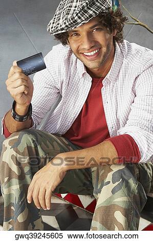 Portrait of a young man holding a credit card and smiling View Large Photo Image Stock Photography - Portrait of a young man holding a credit card and smiling. Fotosearch