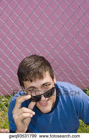 Portrait of a young man holding sunglasses and smiling View Large Photo Image Stock Photo - Portrait of a young man holding sunglasses and smiling. Fotosearch