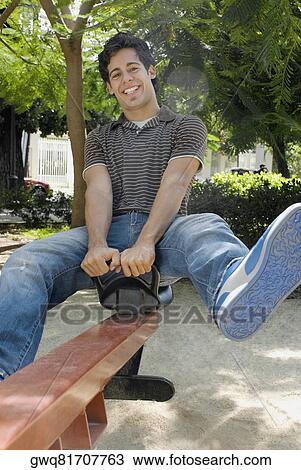 Stock Image - Portrait of a young man on a seesaw. Fotosearch