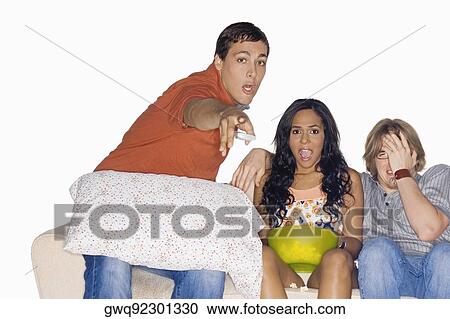 Portrait of a young man pointing forward with his two friends sitting on a couch beside him View Large Photo Image Stock Image - Portrait of a young man pointing forward with his two friends sitting on a couch beside him. Fotosearch
