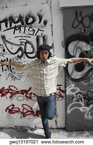 Stock Image - Portrait of a young man posing in front of a wall. Fotosearch