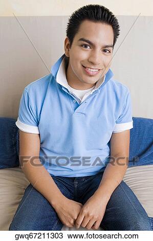 Portrait of a young man sitting on a couch and smiling View Large Photo Image Stock Image - Portrait of a young man sitting on a couch and smiling. Fotosearch