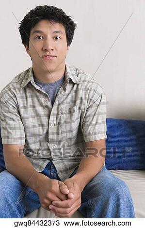 Stock Image - Portrait of a young man sitting on a couch. Fotosearch