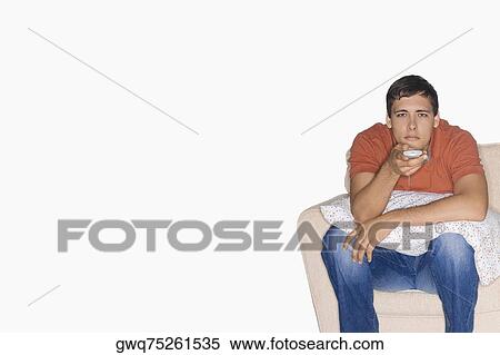 Portrait of a young man sitting on a couch and watching television View Large Photo Image Stock Photography - Portrait of a young man sitting on a couch and watching television. Fotosearch