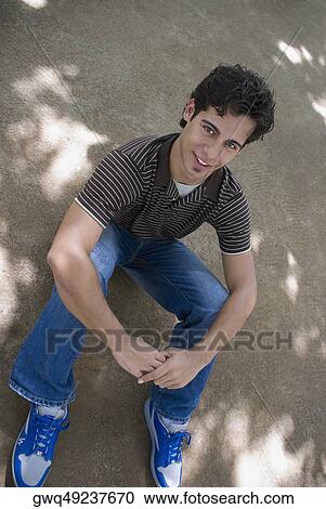 Portrait of a young man sitting with his hand on his knee View Large Photo Image Stock Image - Portrait of a young man sitting with his hand on his knee. Fotosearch