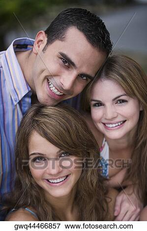 Stock Photo - Portrait of a young man smiling with two young women. Fotosearch