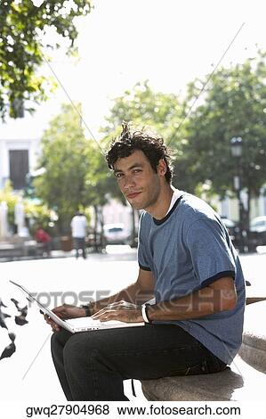 Portrait of a young man using a laptop View Large Photo Image Stock Photo - Portrait of a young man using a laptop. Fotosearch